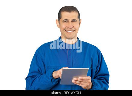 Shot of confident smiling professional handyman in blue overalls using digital tablet with white background. Stock Photo