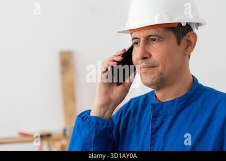 Phone call, construction worker and man at warehouse for building, laugh and maintenance. Mobile, engineer and conversation for inspection, industrial Stock Photo