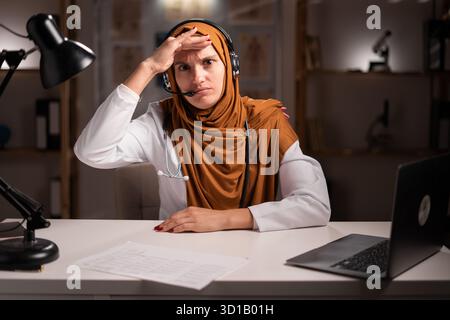 young female Muslim doctor wearing hijab looking away working on night shift at hospital. copy space Stock Photo