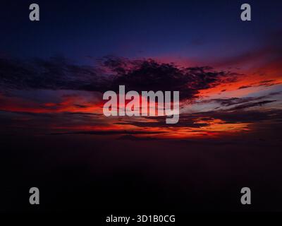 Aerial view of a fiery spectacle unfolds as the sun dips below the horizon, painting the sky with vibrant hues of orange and red, Karanganyar Regency, Central Java, Indonesia. Stock Photo