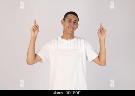 The person is smiling and pointing upwards with both index fingers Stock Photo