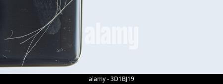 Close-up of a smartphone with cracked screen on light blue background. Stock Photo