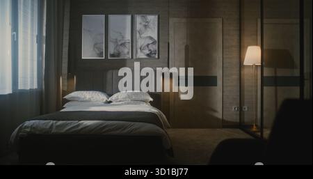 Elegant Mature Hotel Manager in Formal Suit Inspects Luxury Hotel Room, Using Tablet Photograph and Evaluate Bed Arrangement. Concept Hospitality Standards, Quality Control, Professional Management. Stock Photo
