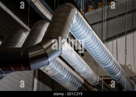 Metal ventilation ducts and air conditioning pipes installed on industrial ceiling showing HVAC system components, air distribution technology and mec Stock Photo