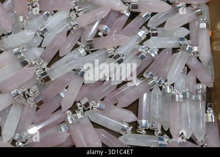 Abstract background texture of Rose quartz crystal point pendants with silver bail caps. Rights Managed detailed full frame material texture for esote Stock Photo