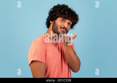 Handsome Young Indian Man Sends a Playful Kiss on Blue Background in Studio Stock Photo