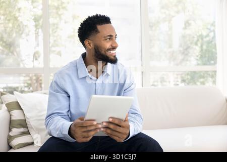 African man sit on sofa with digital tablet device Stock Photo