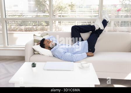 Smiling African man relaxing lying on comfortable couch Stock Photo