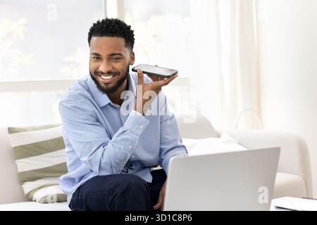 Handsome African man holds mobile phone and listens audio message Stock Photo