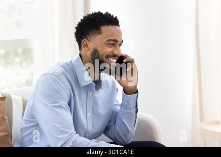 Smiling African man lead pleasant personal talk on smartphone Stock Photo