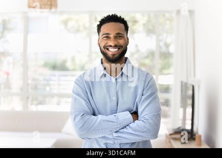 Portrait of handsome African man standing in well-lit living room Stock Photo