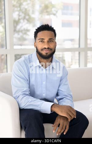 Handsome man sitting on couch looking at camera Stock Photo