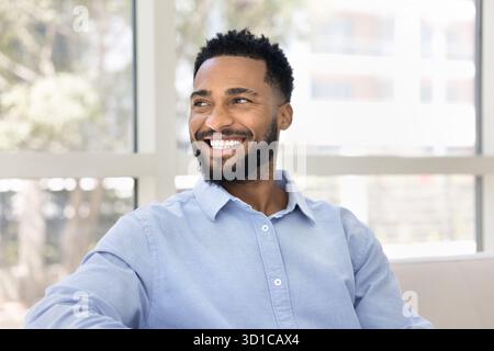 Happy African bearded man relaxing seated on sofa Stock Photo