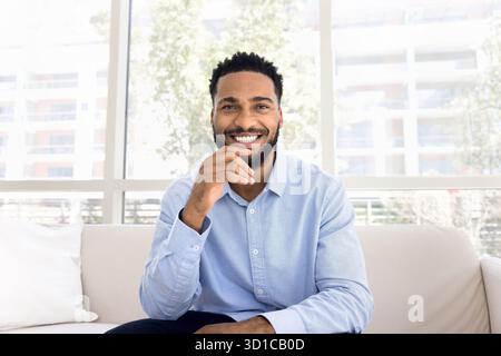Man sitting on sofa gaze at camera with joyful expression Stock Photo