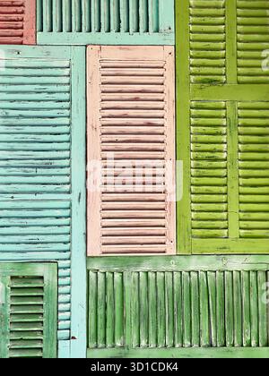 Colourful patchwork wall made of repurposed vintage wooden shutters in shades of green, pink, and blue mallorca Stock Photo