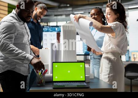Property developers team reviewing blueprints next to copy space display, collaborating on new urban development residential project through city planning and design. Smart city. Stock Photo