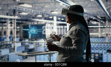 Data center technician using virtual reality, improving AI rigs processing speed. Server hub IT expert using VR headset to manage gear providing support for artificial intelligence workloads, camera B Stock Photo