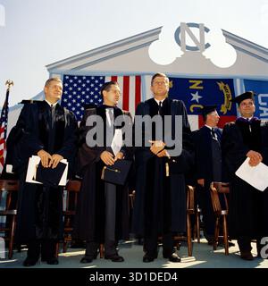 President John F. Kennedy throws the first pitch of the 1962 baseball season. (L-R) Special Assistant to the President Dave Powers; Senator Mike Mansfield of Montana; President Kennedy; Senator Everett Dirksen of Illinois (looking over President Kennedy’s shoulder); Representative Charles Halleck of Indiana; Joseph Cronin, President of the American League of Professional Baseball Clubs; Secretary of the Treasury C. Douglas Dillon (seated in front); General Elwood “Pete” Quesada, majority owner of the Washington Senators; Bob Scheffing, Manager of the Detroit Tigers. Stock Photo