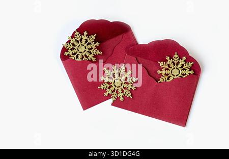 Two red envelopes with golden snowflakes on white background. Holiday greeting card, invitation or Christmas message template. Festive season decorati Stock Photo