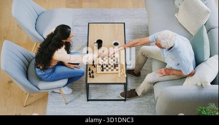 Chess, woman and grandpa handshake on sofa for congratulations, board game and mental challenge. Problem solving, above and people shaking hands for Stock Photo