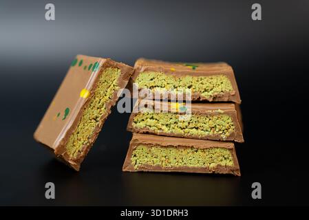 Luxurious pistachio chocolate bars stacked neatly on black background, ideal for confectionery branding and gourmet advertising.  Stock Photo