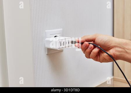 female hand insert a plug of the phone charger into socket at home Stock Photo