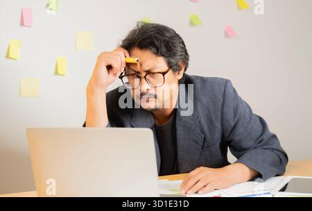 Shot of a adult businessman looking stressed while working in a modern office. Selective focus. Stock Photo