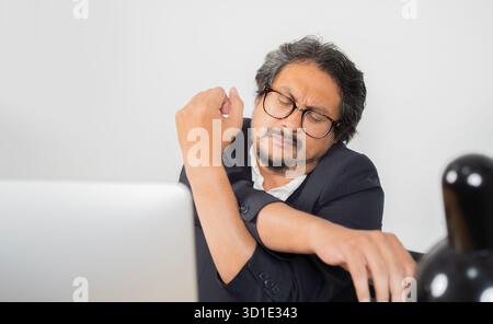 Business man stretching and working at home, adult man relax at desk, stretching and resting in home office. Businessman stretching arms overhead. Stock Photo