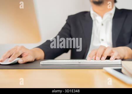 Businessman using computer with hands typing on a keyboard and holding computer mouse on workplace. Stock Photo