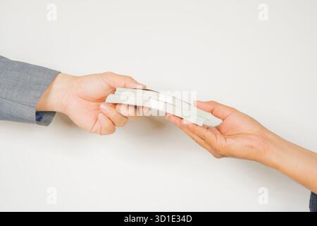 Hands of two people holding two stack of dollar banknote on a white background. Close-up. Stock Photo