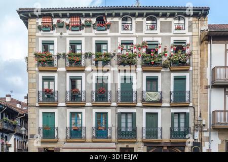 Symmetrical Facade of a Traditional Basque Building Adorned with Flower Pots and Iron Balconies, European Architecture Stock Photo