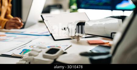 A modern workspace featuring a close-up of a robot hand collaborating with a human during a meeting, analyzing charts and graphs on the table that sym Stock Photo