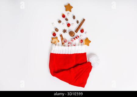 Cookies, cinnamon sticks and Christmas tree toys are laid out in the shape of a Christmas tree on a white isolated background, flat lay with a place f Stock Photo