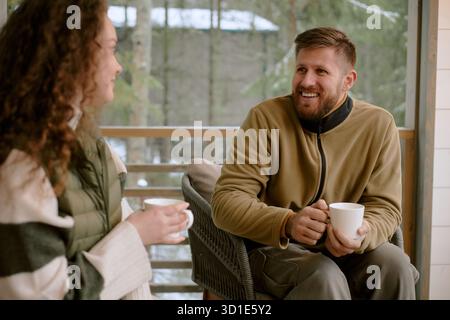 Caucasian Young Adult Man Smiling While Talking with Young Adult Woman Outdoors Stock Photo