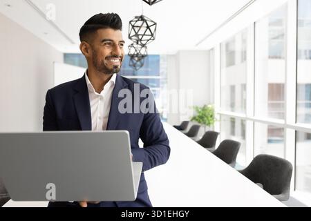 Happy young Indian business expert man using laptop Stock Photo