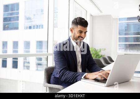 Positive cheerful Indian CEO man working on successful online project Stock Photo