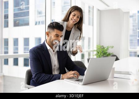 Diverse couple of business professionals meeting and laughing at laptop Stock Photo