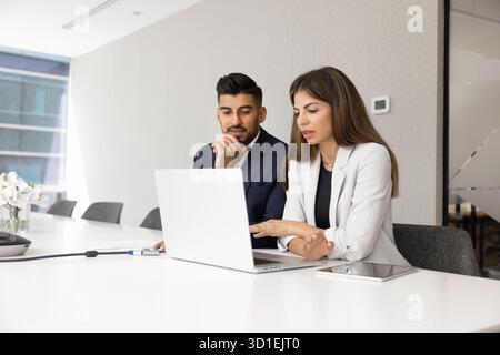 Diverse couple of serious managers talking at laptop Stock Photo