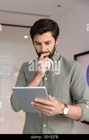 Thoughtful young 30s businessman using digital tablet Stock Photo
