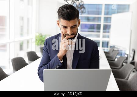 Pensive focused young Indian CEO man using laptop Stock Photo