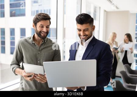 Cheerful multiethnic male managers watching online media content on laptop Stock Photo