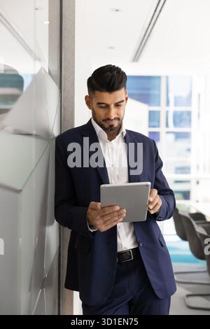 Serious young Indian CEO man typing on tablet Stock Photo