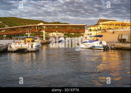 Several boats and catamarans are moored on the jetty in the port of Saint-Gilles, whose water reflects the warm reflections of sunset light and the su Stock Photo