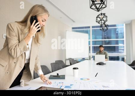 Positive busy analyst woman talking on mobile phone Stock Photo