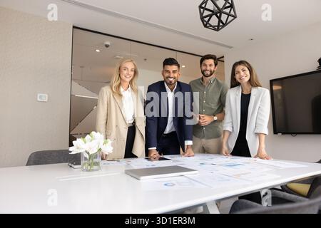 Creative team of positive young diverse professionals standing at table Stock Photo