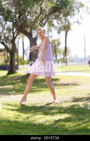 Woman dancing barefoot on green grass in park Stock Photo