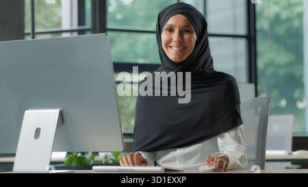 Islamic Muslim business woman in hijab typing computer in company office businesswoman female girl executive marketing startup agent working smiling Stock Photo