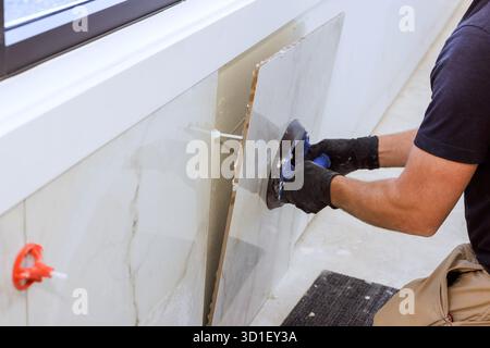 Skilled worker using vacuum suction cup tool tile piece to fit into wall in contemporary indoor space. Stock Photo