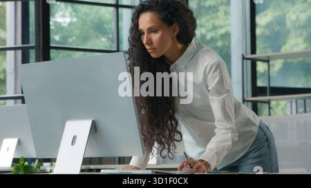 Busy concentrated Hispanic business woman typing computer checking data in documents papers businesswoman checking work result female girl manager Stock Photo