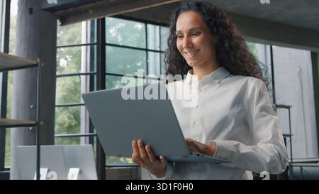 Successful Hispanic business woman typing computer in modern office businesswoman smiling happy female girl manager happy working with laptop remote Stock Photo